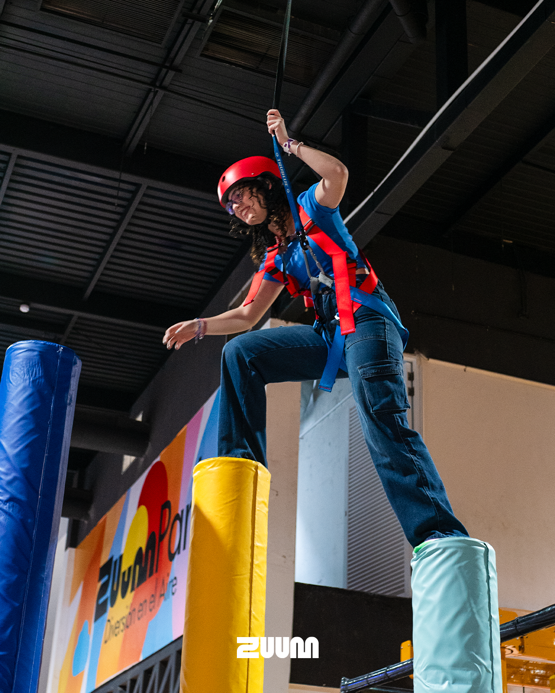 high angle shot of a massive indoor trampoline park tower with neon accents and safety padding